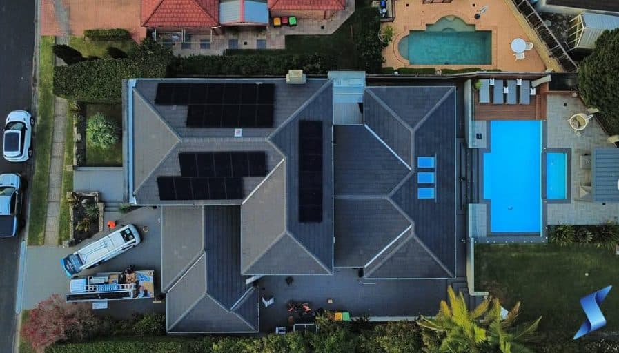 Aerial view of a home with solar panels and a pool